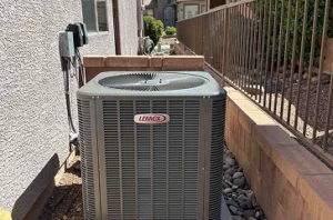 A Lennox air conditioning unit is installed outside a house next to a brick wall and a metal fence.